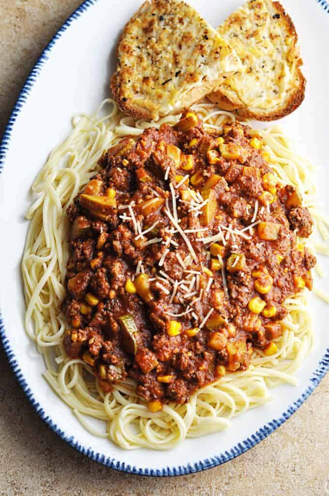 Pasta sauce with zucchini and corn on top of linguini