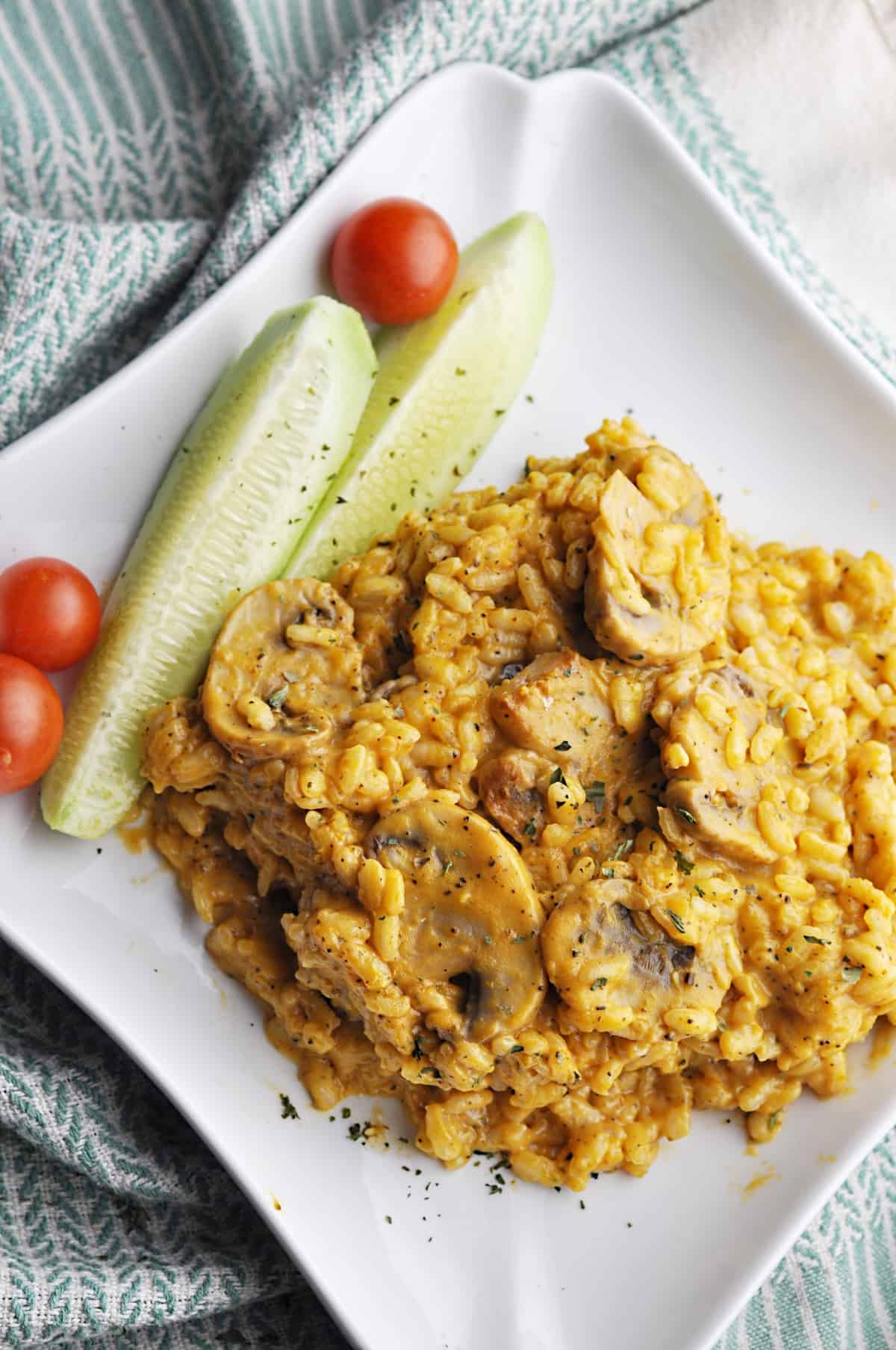 Risotto with mushrooms and pumpkin served with cucumbers and tomatoes on plate