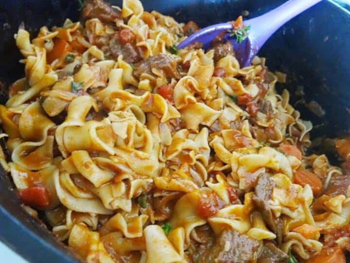 Making goulash in Dutch oven pot with noodles