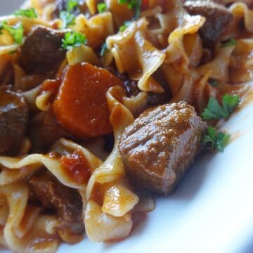 Beef goulash with egg noodles and veggies on plate