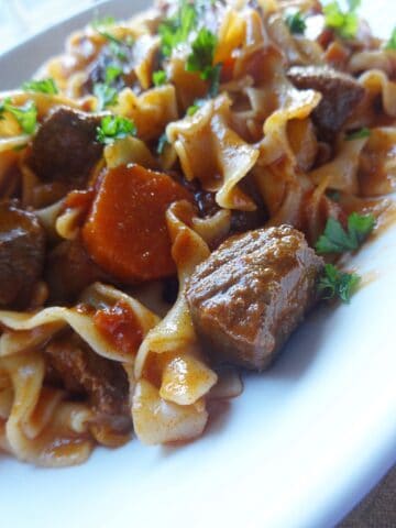 Beef goulash with egg noodles and veggies on plate