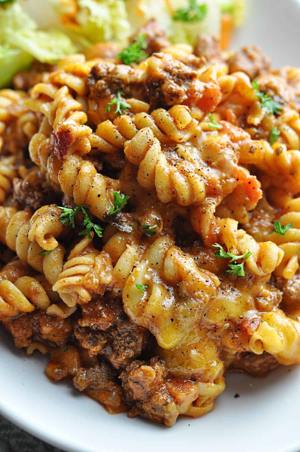 Pasta with ground beef and cheese served on plate.