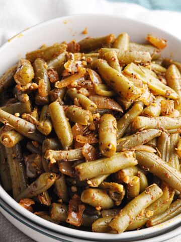 Cooked green beans with spices served in bowl.