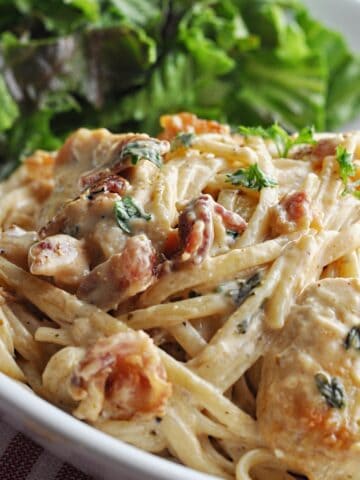 Creamy linguini with chicken and bacon served on plate with salad