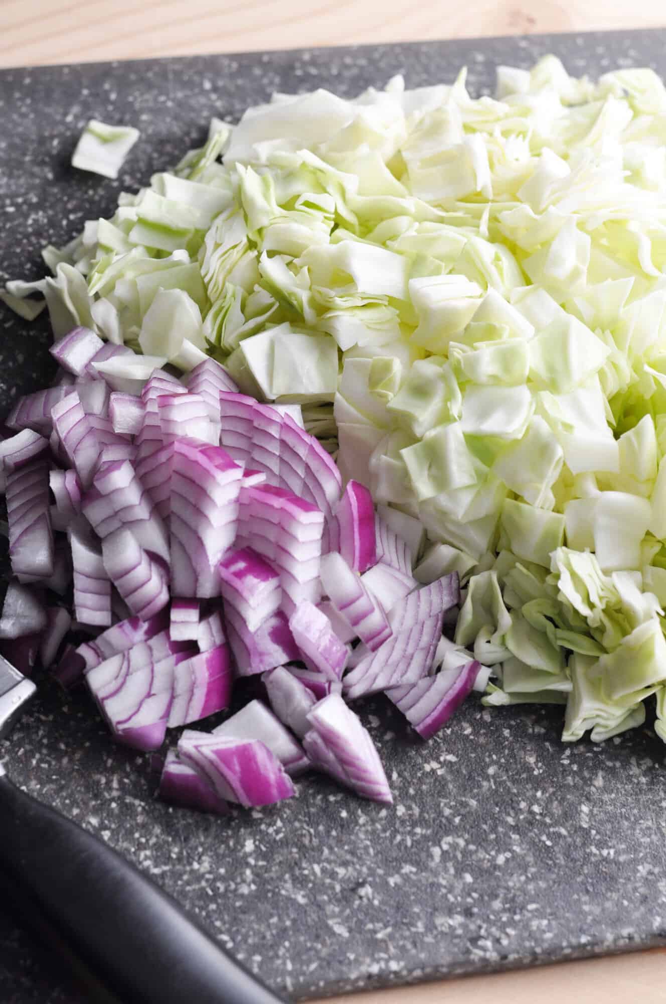 Chopped cabbage and red onions on cutting board