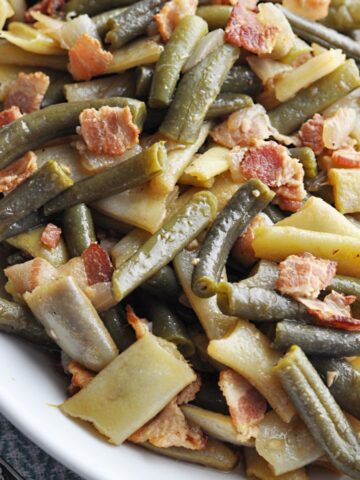 Cooked green beans with bacon served on a plate.