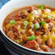 Up close chili in bowl with beans, cheese, and green onions.
