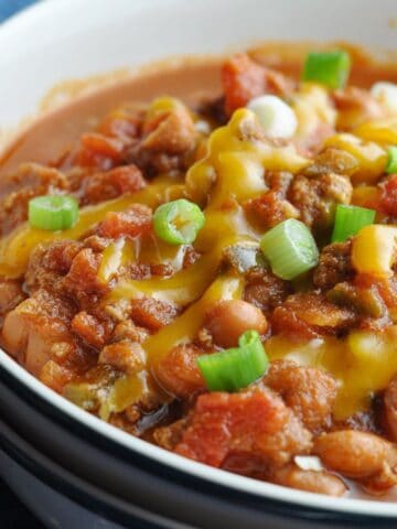 Up close chili in bowl with beans, cheese, and green onions.