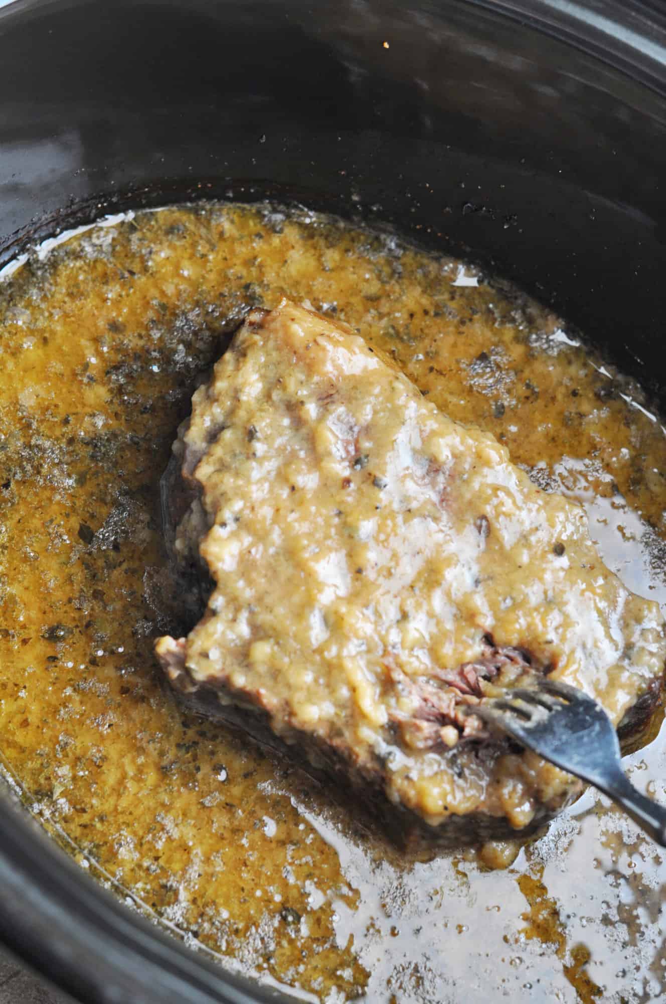 Beef roast cooked in slow cooker with gravy.