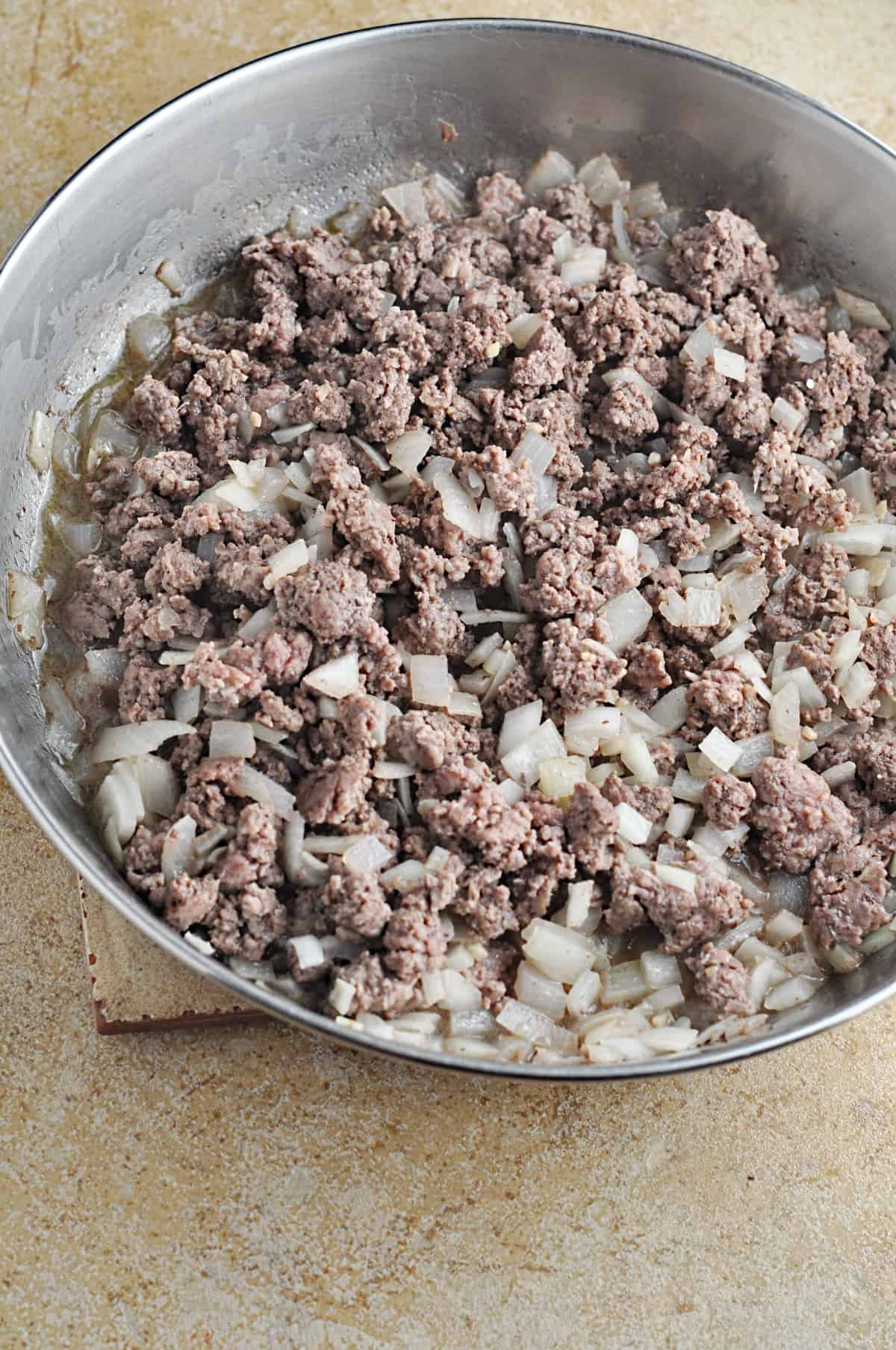 Cooked ground beef and chopped onions in skillet.