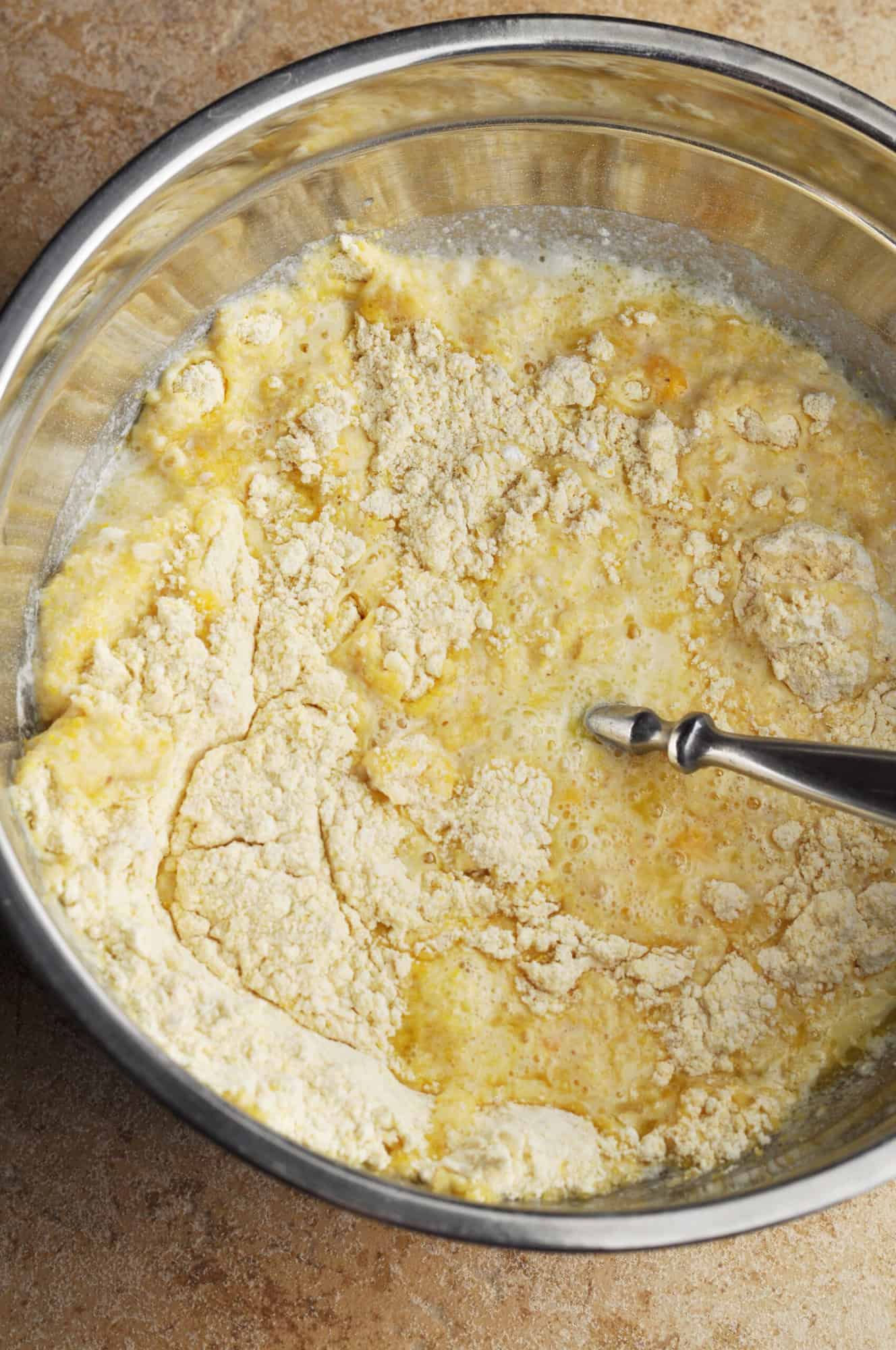 Cornmeal with eggs, milk, and melted butter mixed up in bowl.
