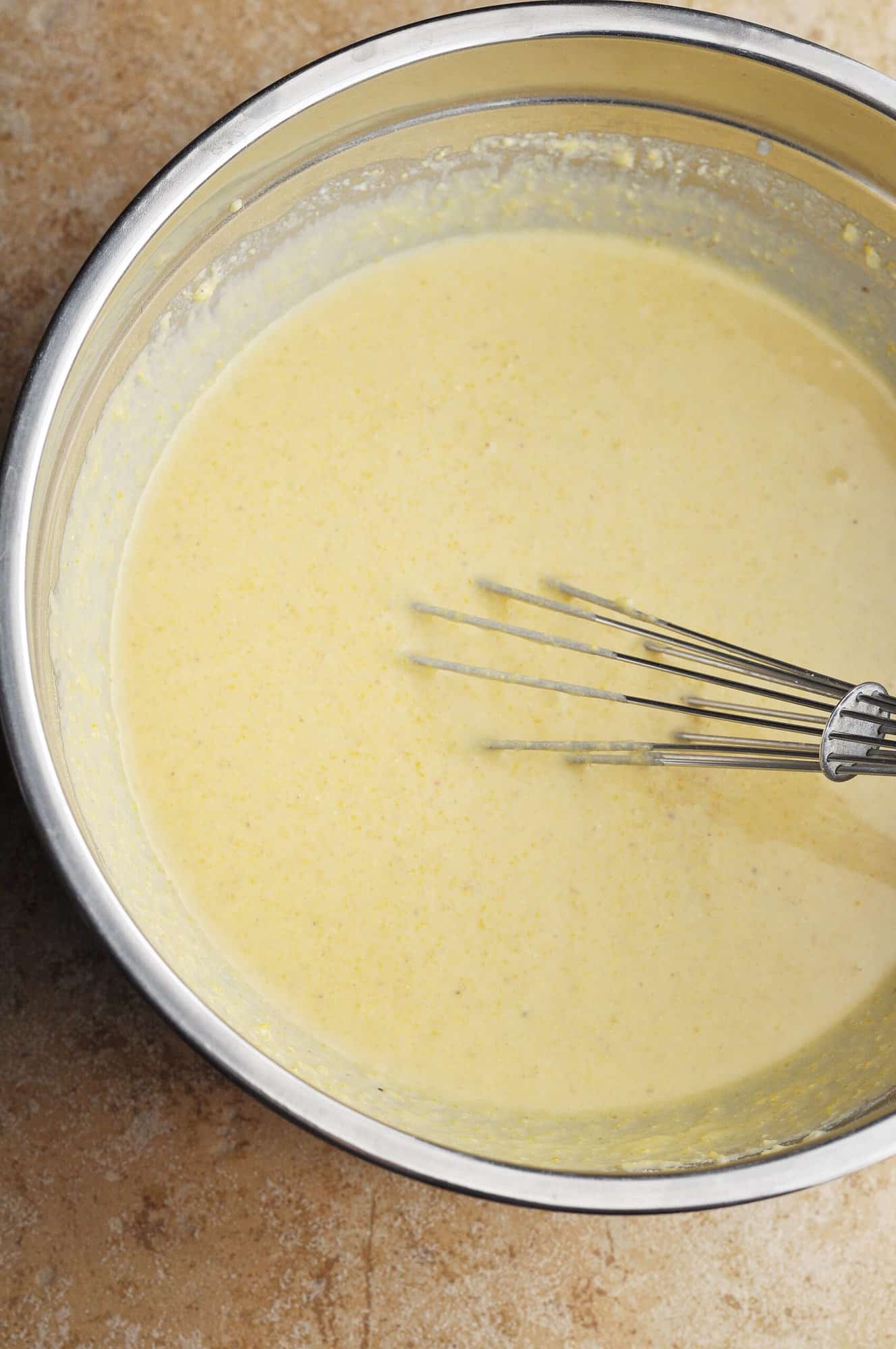 Cornbread ingredients mixed with whisk in bowl.