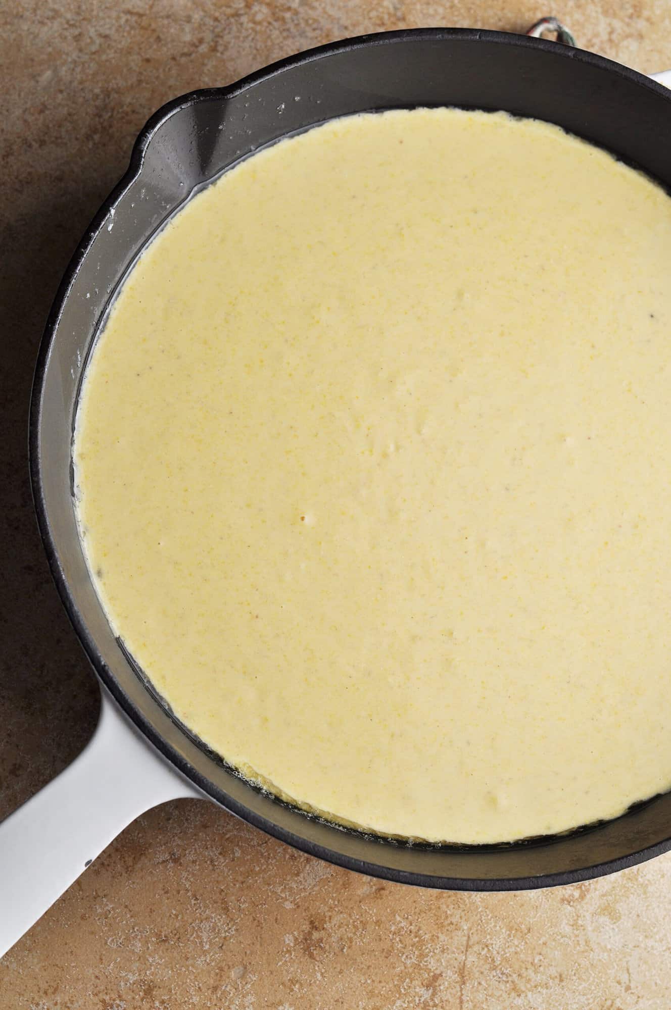 Cornbread mixture in cast iron skillet ready to bake.