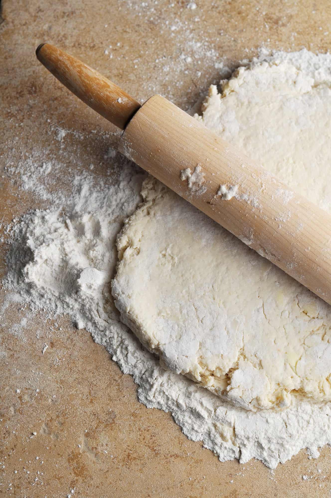 Biscuit dough rolled out on floured surface with rolling pin.