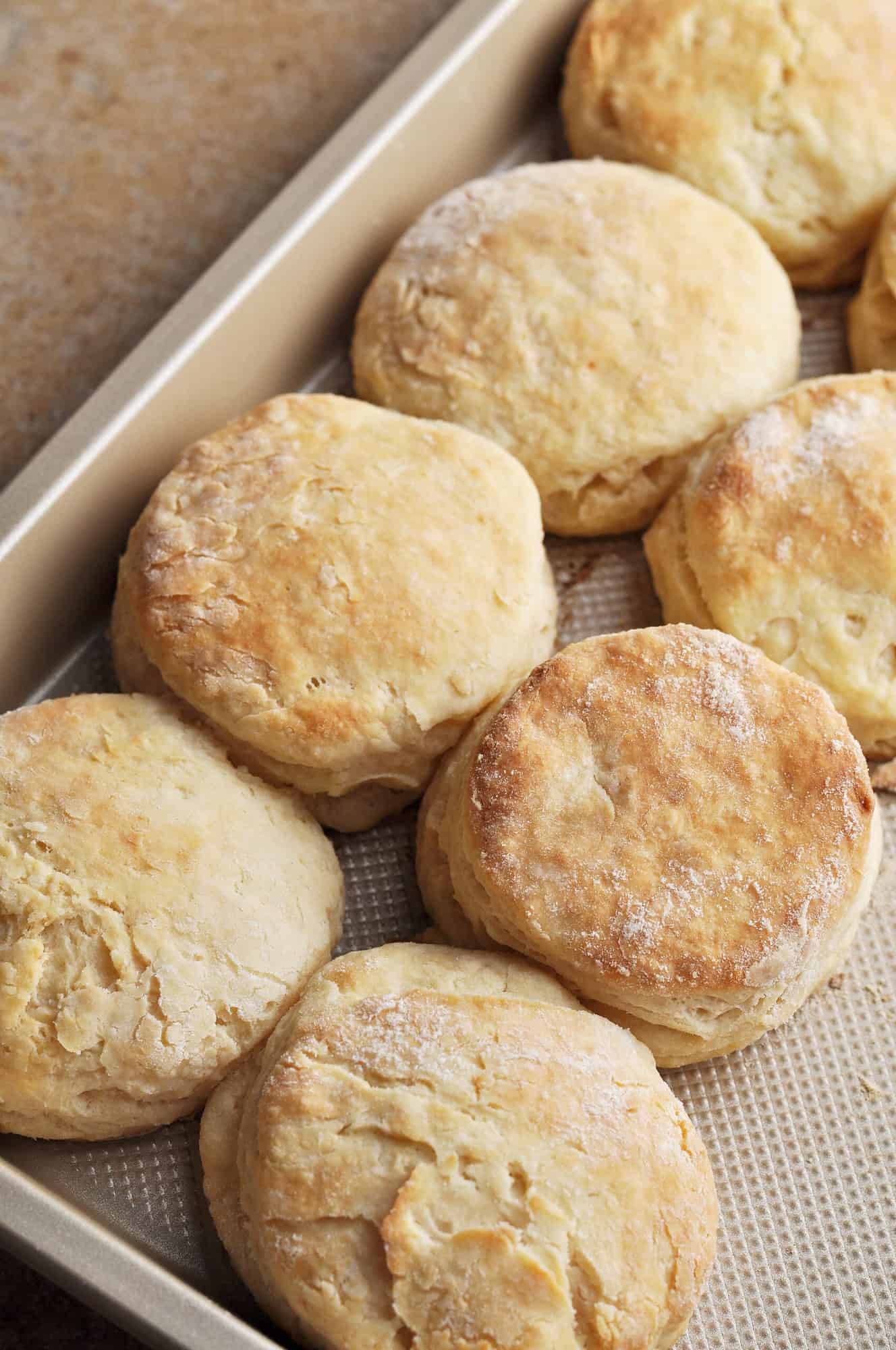 Cooked biscuits lined up on baking pan.
