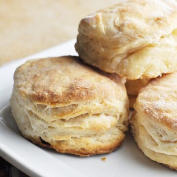 Cooked flaky biscuits stacked on plate ready to serve.