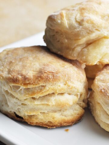 Cooked flaky biscuits stacked on plate ready to serve.