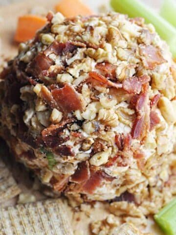 Bacon and walnut covered cheese ball served with crackers, celery, and carrots.