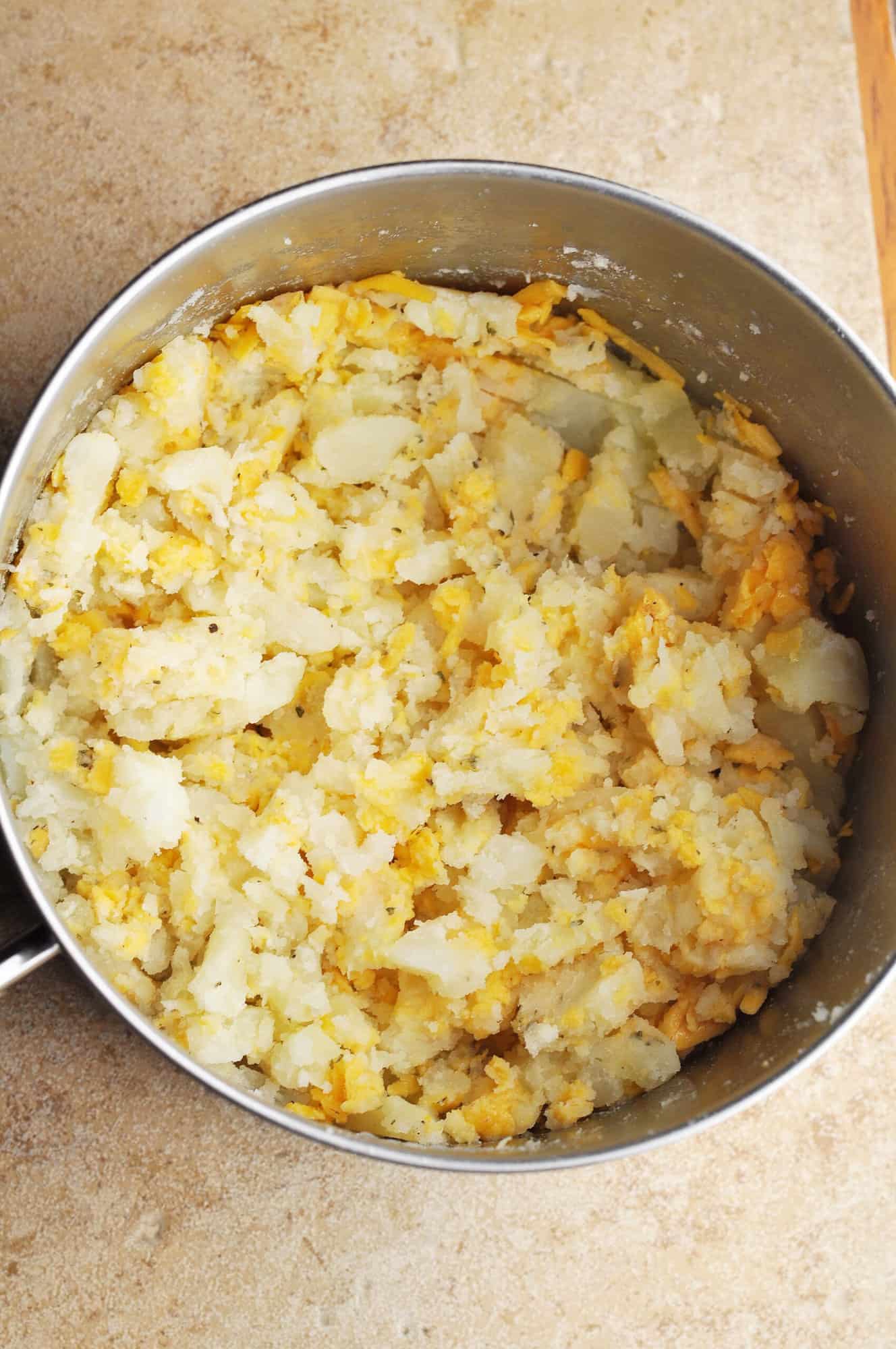 Cooked potatoes and cheese in pot.