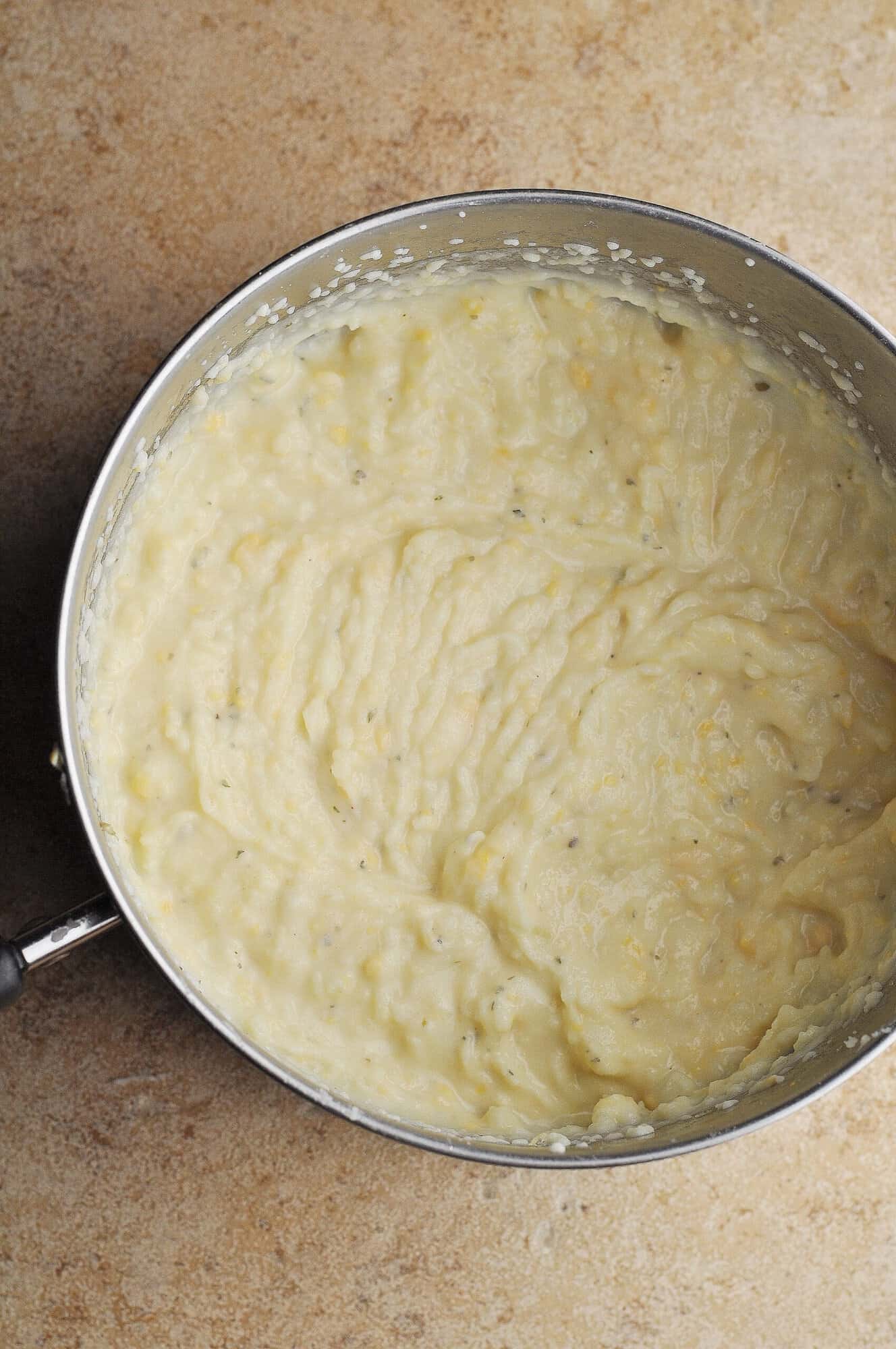 Blended mashed potatoes with cheese in pot.