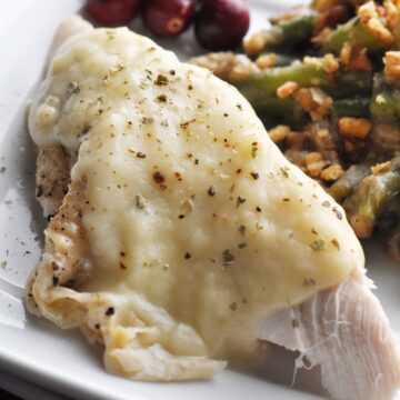 Gravy and ground black pepper on top of turkey slice on plate.