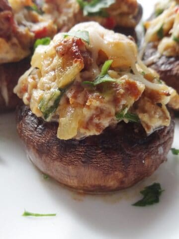 Cooked mushroom stuffed with sausage, onion, and cheese on plate.