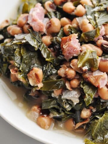 Black eyed peas, collard greens, and ham served in bowl.