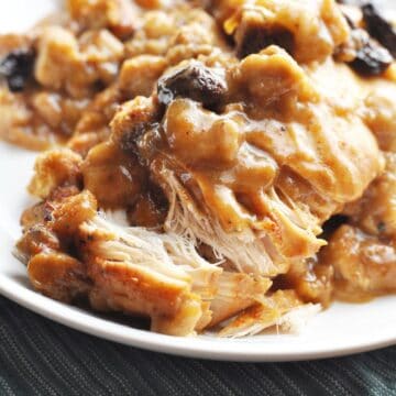 Chicken with stuffing, gravy, and cranberries on a plate ready to eat.