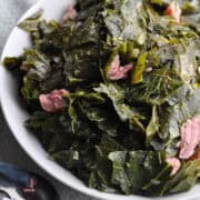 Collard greens with ham in small bowl with spoon ready to serve.