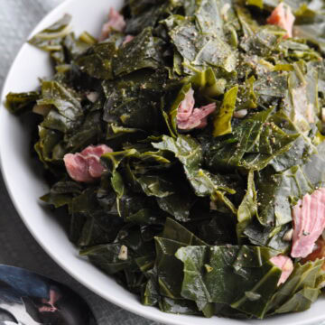 Collard greens with ham in small bowl with spoon ready to serve.